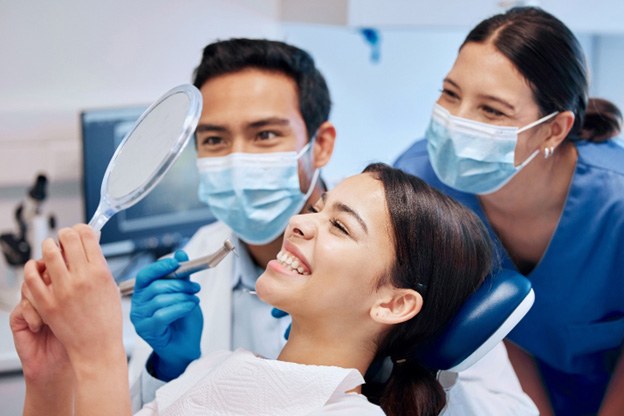 Woman and dental team smiling in a mirror
