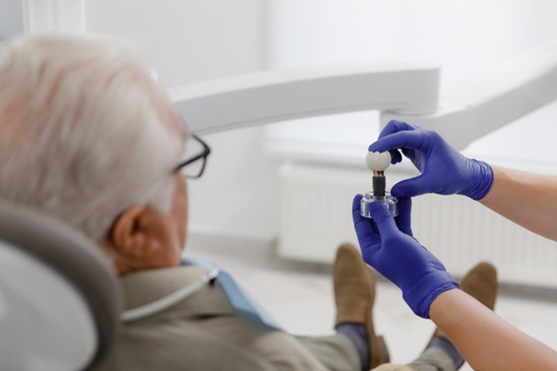 Dentist showing patient a dental implant model