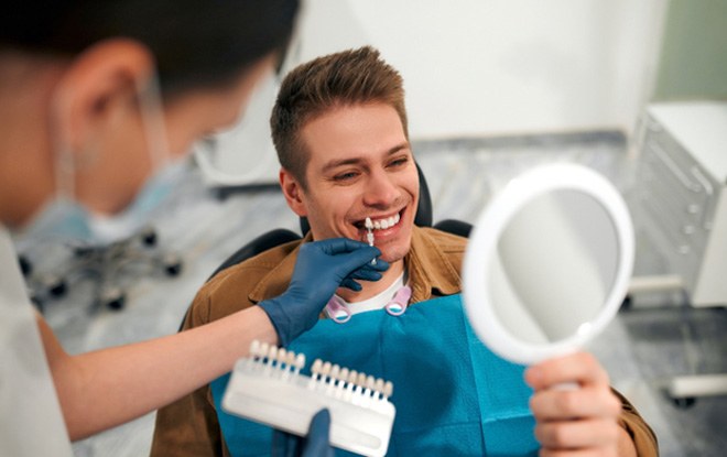 Man and dentist checking tooth shade