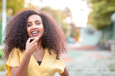 Patient in Plain City putting Invisalign on teeth