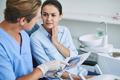 Patient in Plain City holding cheek at dentist office